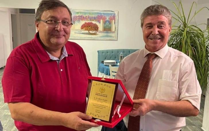 Bakan Üstel, Girne Özyalçın Aşı Merkezi’nde gönüllü olarak hizmet veren Dr. Bülent Dizdarlı’ya plaket takdim etti